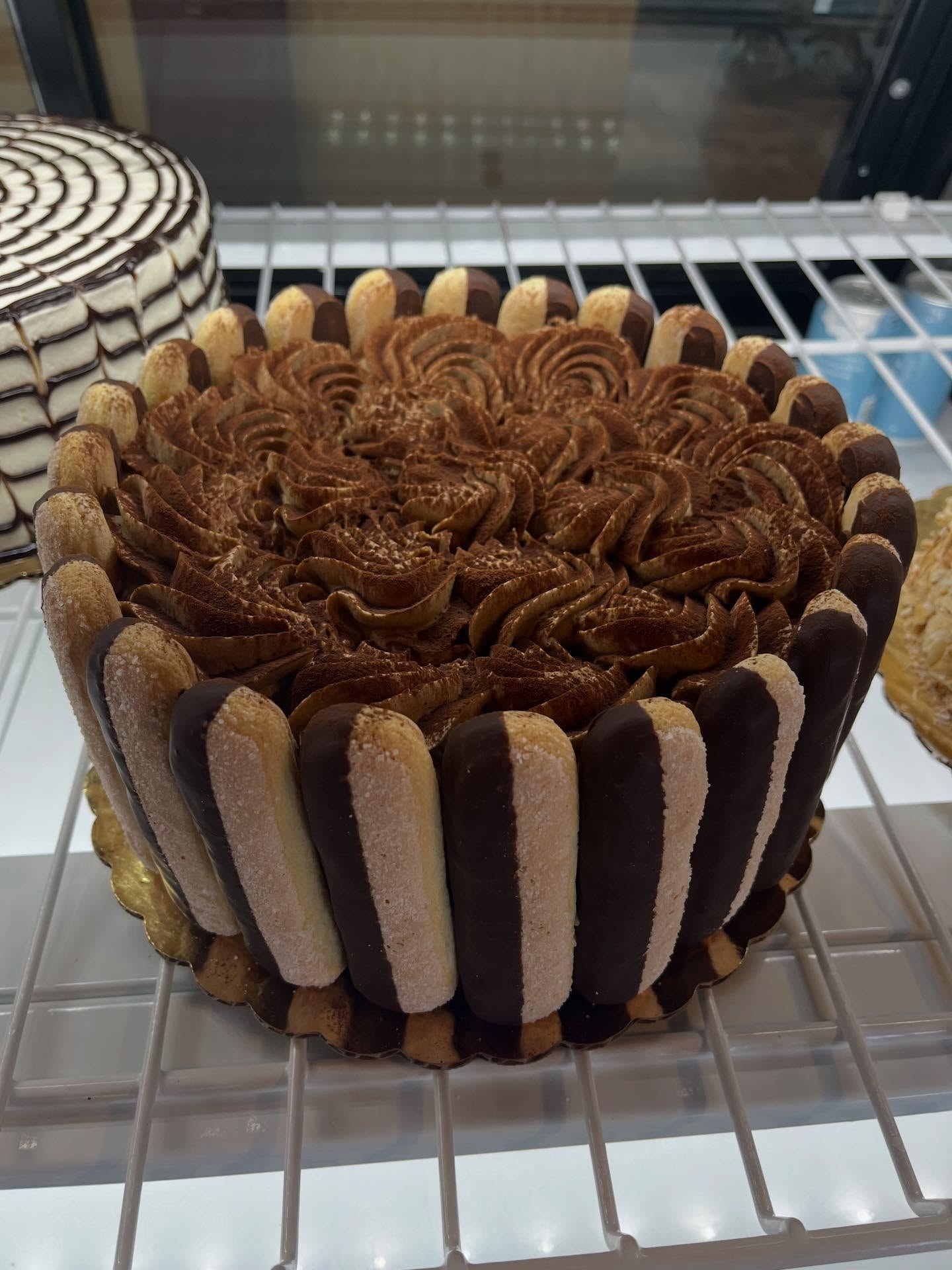 Tiramisu cake with ladyfinger cookie sides and chocolate rosette frosting
